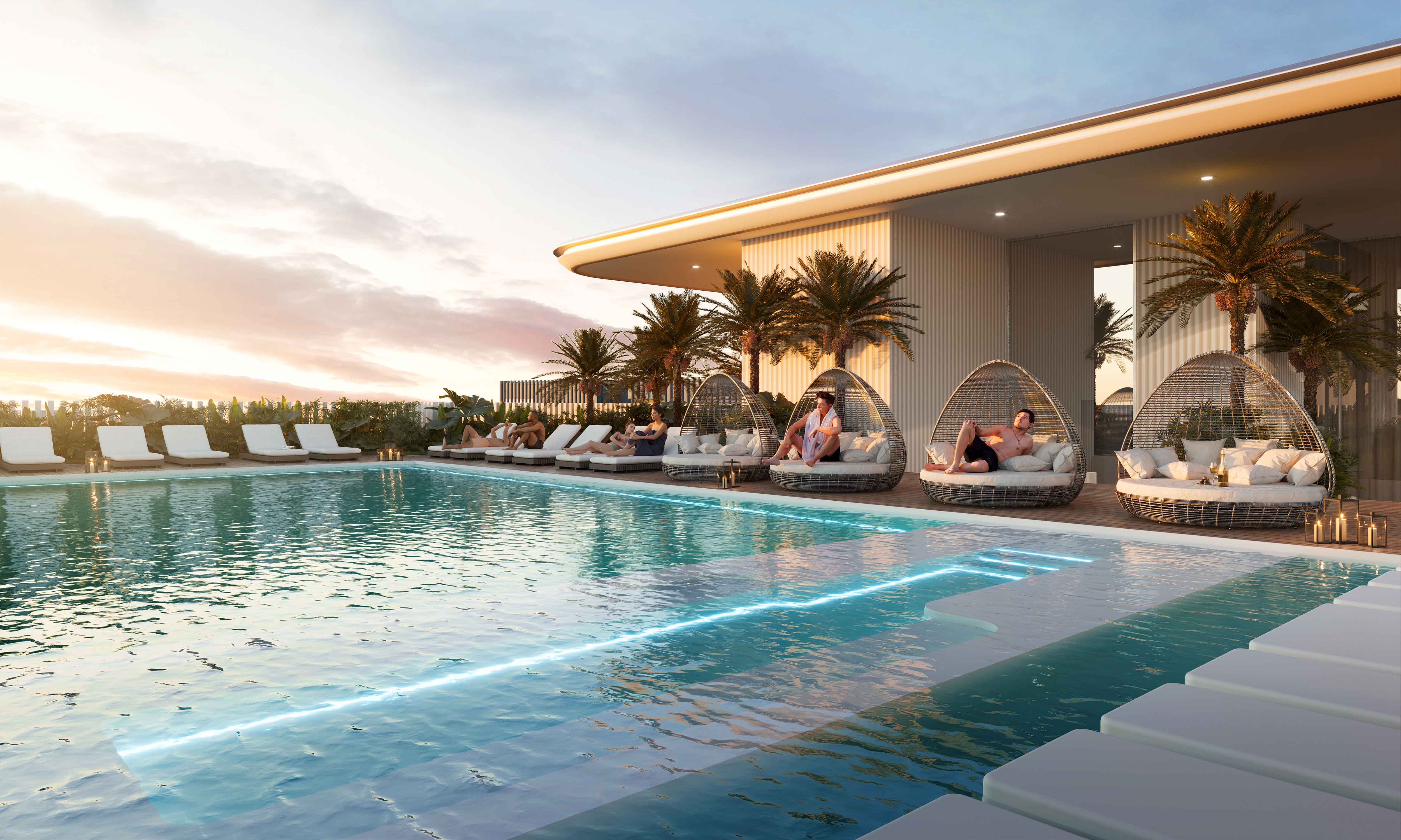 Cove Edition I By Imtiaz 1 A luxurious pool area with lounging chairs, woven egg chairs, palm trees, and a sunset sky in the background.